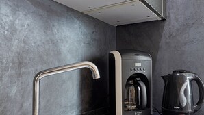 Una cucina moderna con lavello in acciaio inossidabile, macchina da caffè e bollitore.
