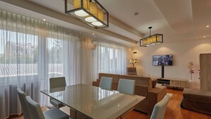Un soggiorno moderno con tavolo da pranzo in vetro, divani color beige e televisione a parete.