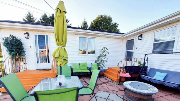 A patio area with green chairs, a table, and a swing seat.