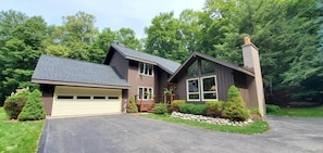 A two-story house with a garage, a large front porch, and a stone retaining wall.