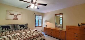 A bedroom with a bed, a dresser, a mirror, a ceiling fan, and a window with blinds. - Fairway House Close to Crystal Lake Golf (Beulah)