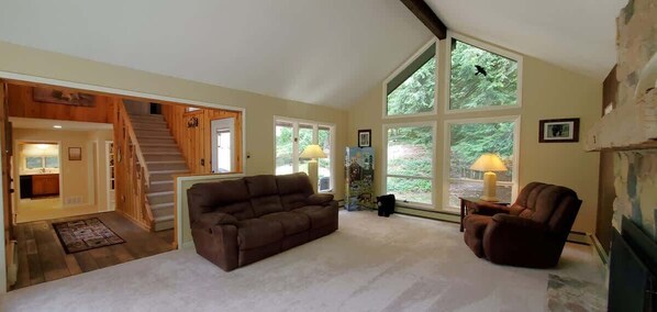 A spacious living room with a large window, a staircase, and a cozy fireplace.
