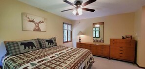A bedroom with a bed, a dresser, a ceiling fan, a window, and a wall-mounted mirror.