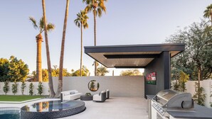 A modern outdoor patio with a pool, seating area, and a barbecue station. - Scottsdale Retreat Outdoor Oasis w/Heated Pool & Spa, Outdoor Kitchen & 100" TV (Scottsdale)