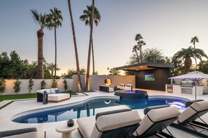 A modern outdoor pool area with lounge chairs, a hot tub, and a barbecue setup. - Scottsdale Retreat Outdoor Oasis w/Heated Pool & Spa, Outdoor Kitchen & 100" TV (Scottsdale)