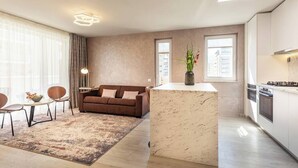 A modern living room with a brown sofa, a marble island, and a dining area with chairs and a table.