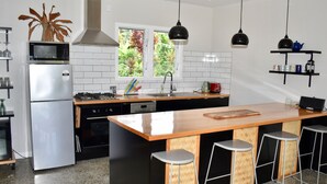 Una cucina moderna con isola centrale, sgabelli da bar, microonde, piano cottura e lavello.