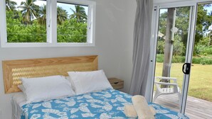 Una camera da letto con un letto, un comodino e vista su un giardino tramite una porta scorrevole.