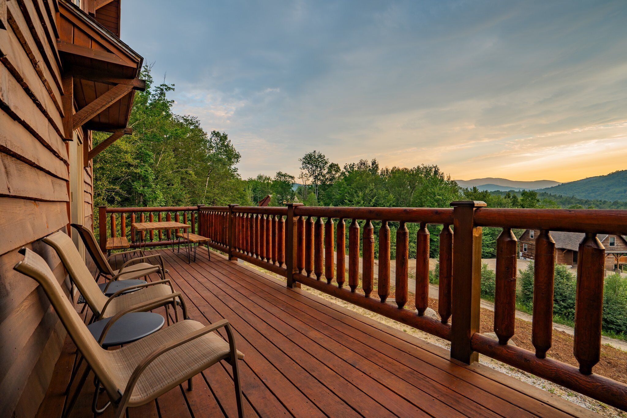 Una terraza de madera con mobiliario exterior y vistas del paisaje circundante.