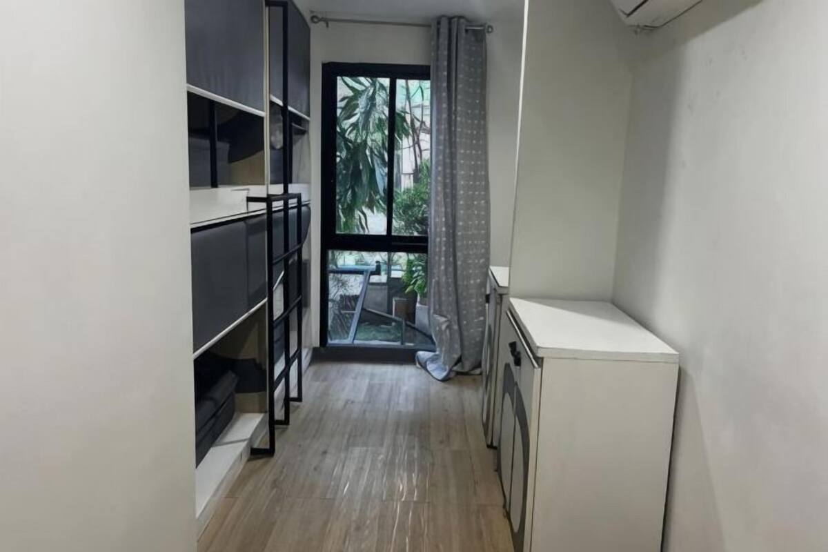 A narrow hallway with a bunk bed, a small table, and a window with a view of palm trees.