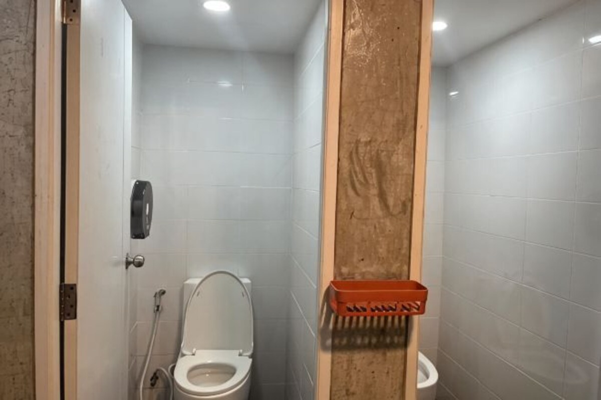 Ein Badezimmer mit Toilette, Handtrockner und Mülleimer.