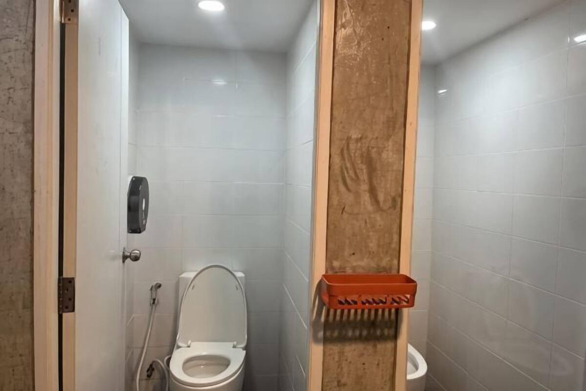 A bathroom with a toilet, a hand dryer, and a trash bin.