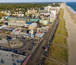 Vista aérea de un pueblo costero con una playa, un estacionamiento y varios edificios, incluyendo un hotel con un letrero destacado.
