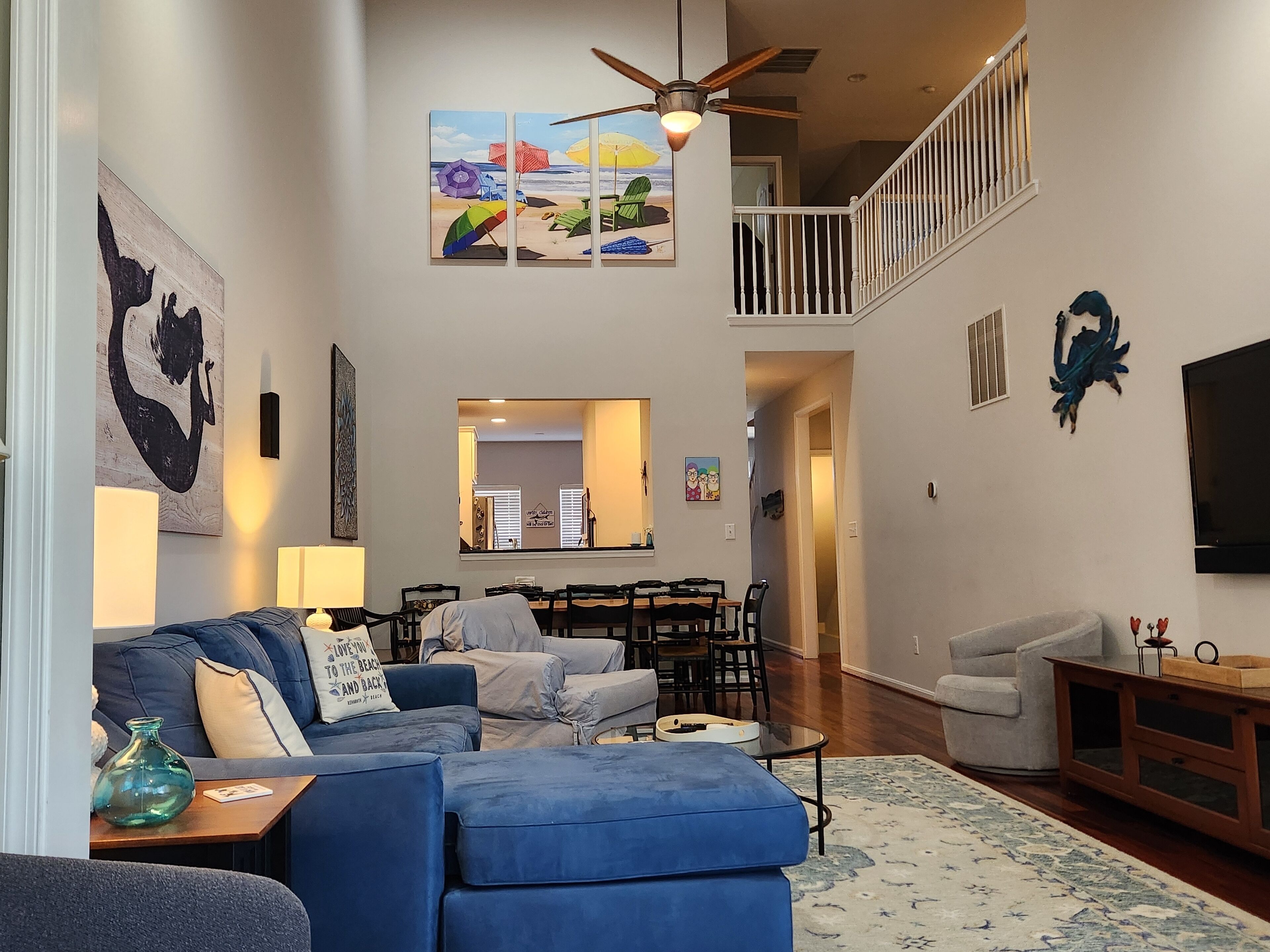 A spacious living area with a blue sofa, a dining table, and a staircase leading to an upper level.