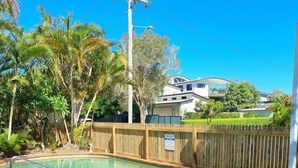 A swimming pool with a wooden fence and a grassy area. - Golden Beach Holiday Park (Golden Beach)
