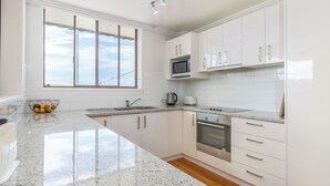A modern kitchen with white cabinets, a granite countertop, a stainless steel oven, and a window with a view.