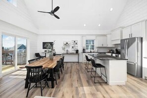 A spacious kitchen with a central island, white cabinetry, and a dining area with a wooden table and chairs.