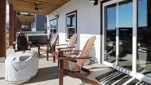 Een overdekt terras met houten stoelen en een beschutte zithoek.