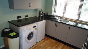 Una cocina compacta con lavadora, un lavabo y armarios.