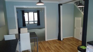 Una habitación con una mesa de comedor y sillas, una escalera y una puerta que da a otra estancia.