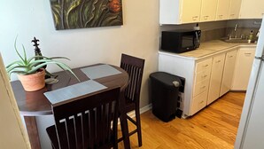 Una cocina compacta con armarios blancos, un microondas y un pequeño cubo de basura.