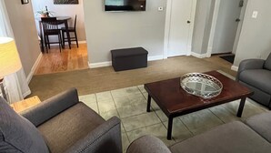 Una sala de estar con televisor, una mesa de centro y dos sofás.