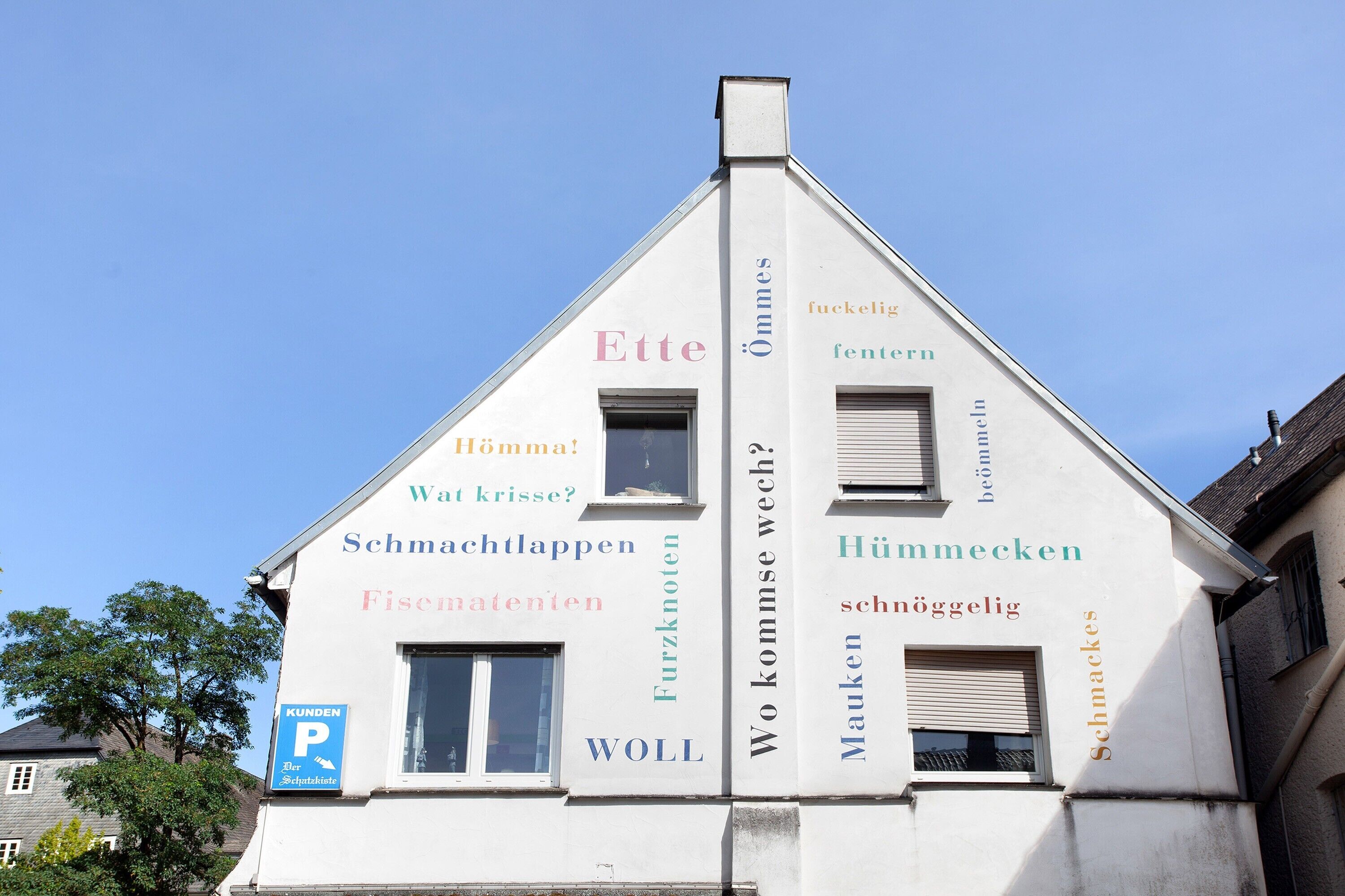 Ein Gebäude mit mehreren Fenstern und einem Schild mit verschiedenen Wörtern in unterschiedlichen Farben.