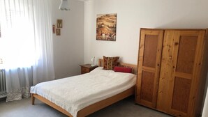 Une chambre à coucher avec un lit, une table de chevet, une lampe, une armoire et un tableau au mur.