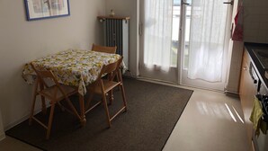 Un coin repas avec une table et des chaises, un radiateur, une horloge et une vue à travers une porte vitrée.