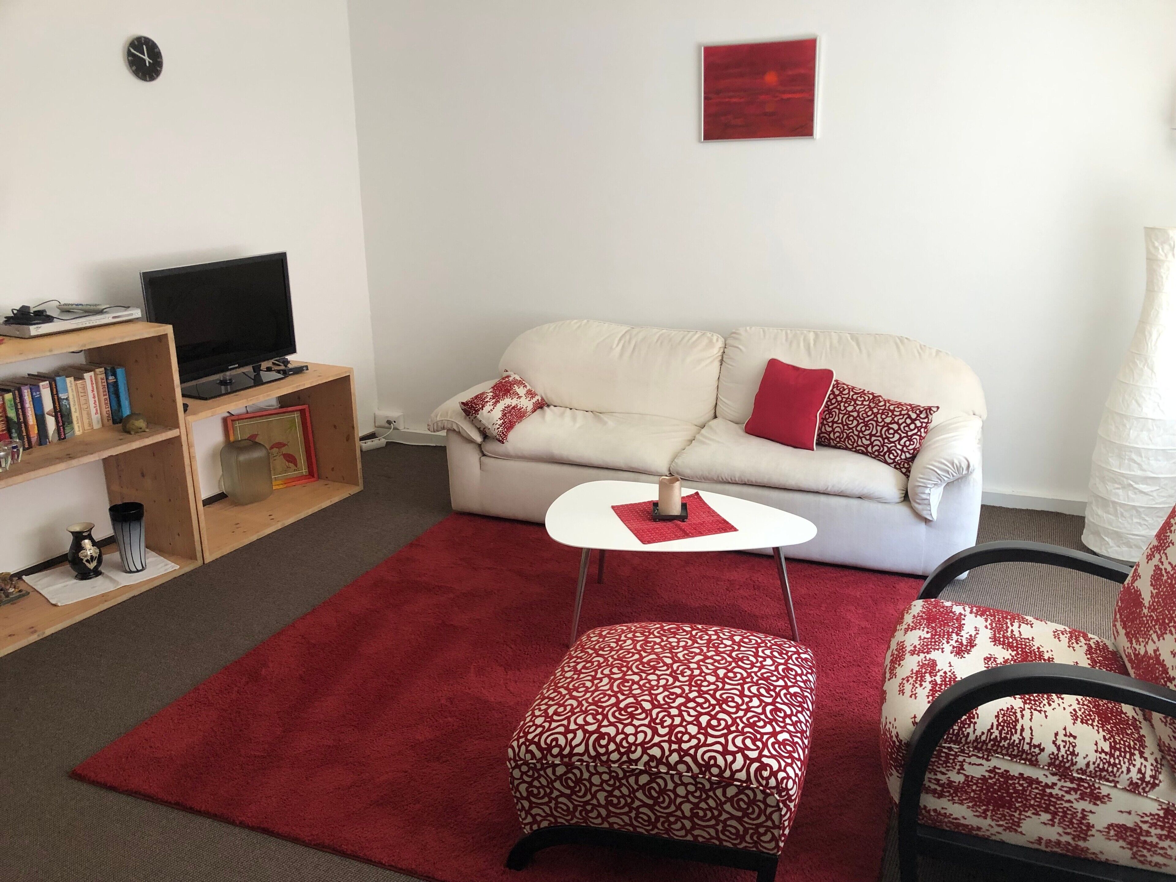Una sala de estar con un sofá, una mesa de centro, una estantería y un televisor.