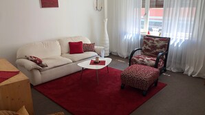 Un salon avec un canapé, un fauteuil, une table basse et un tapis rouge.