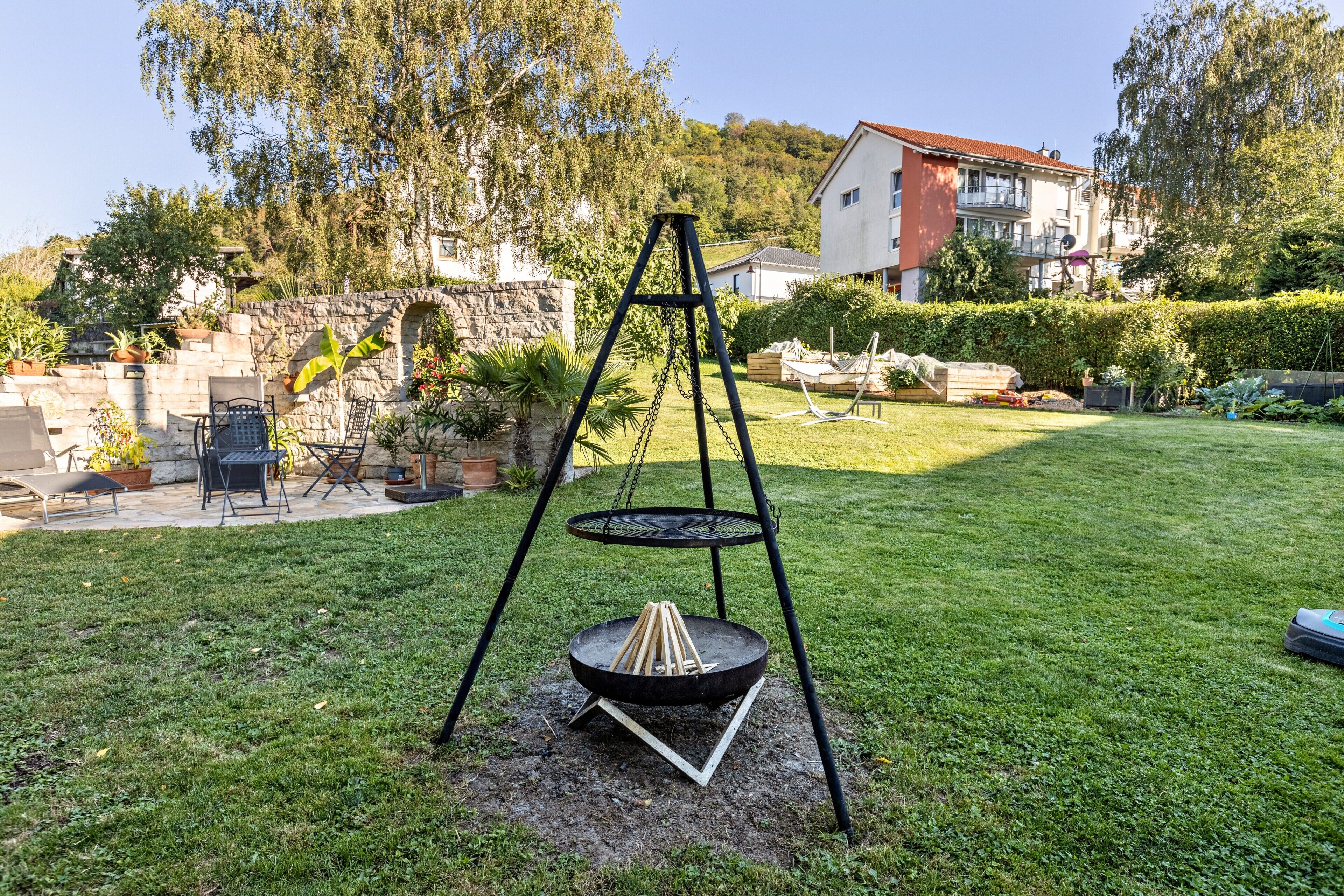 Un giardino sul retro con altalena, un braciere e un muro in pietra.