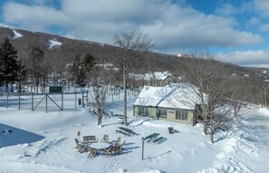 A snow-covered outdoor area with a building, tables, chairs, and a bench. - OKEMO WINTERPLACE Best Location, Ski-In/Ski-Out 4BR/3BATH + LOFT.  Spacious. (Ludlow)