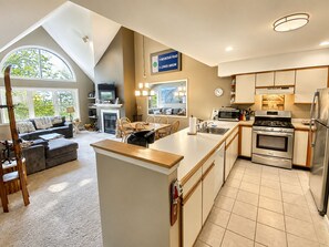 A modern kitchen with a central island, a dining area with a view, and a living room with a fireplace.