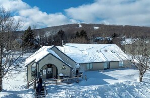 A building with a snow-covered roof, a sign reading 'POOL', and a clear sky.