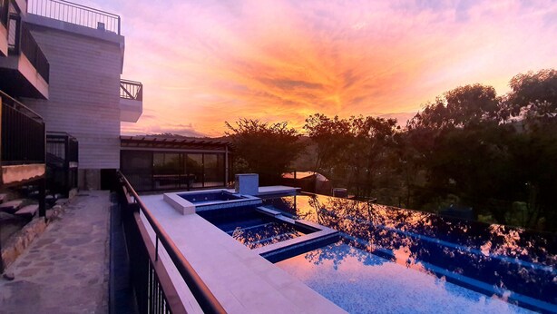 Un bâtiment moderne doté d’une piscine et offrant une vue sur le coucher de soleil.