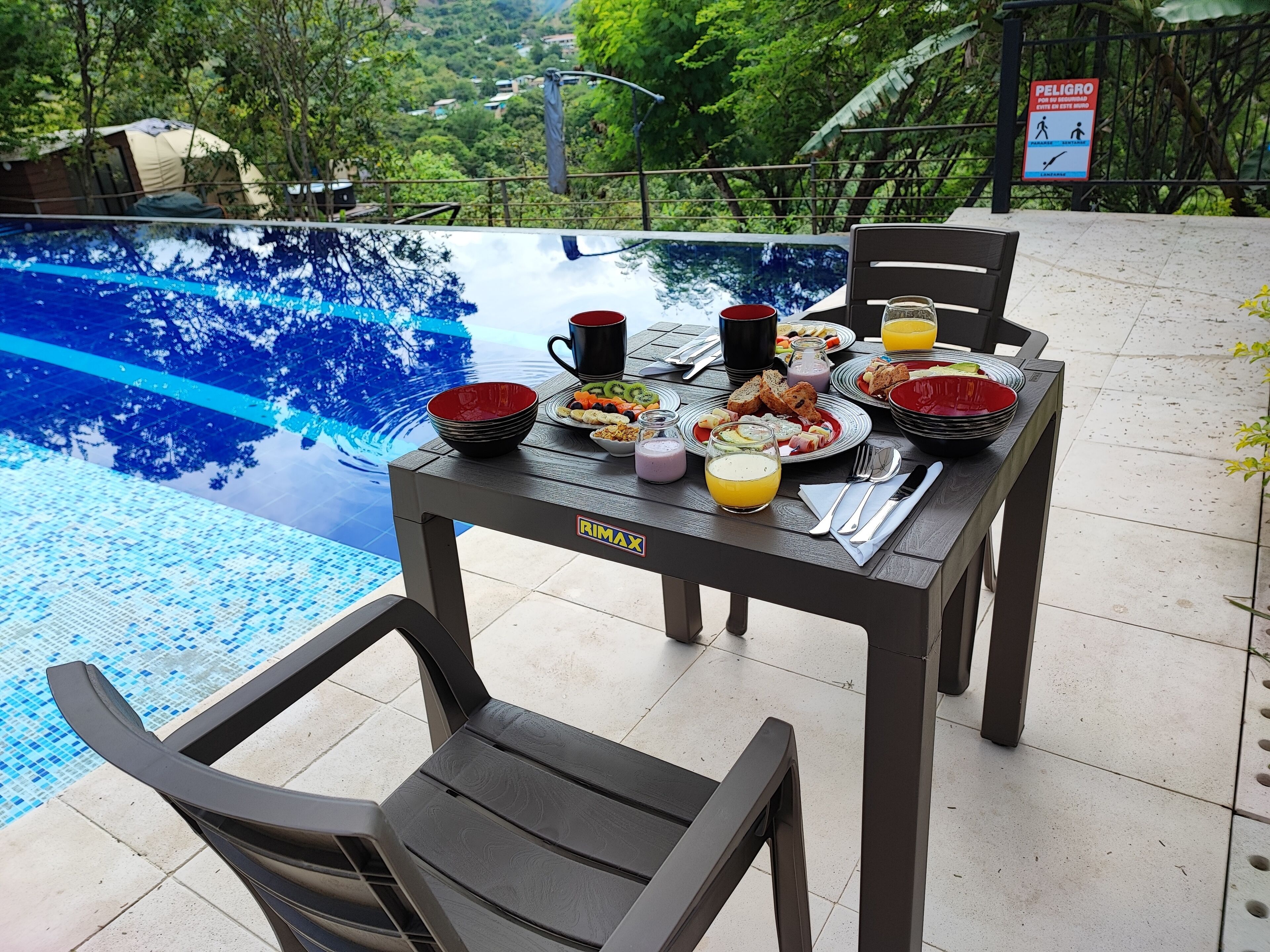 Une table à manger avec des aliments pour le petit-déjeuner et une vue sur la piscine.