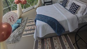 Une pièce aménagée avec une tente, un lit, des oreillers, une couverture et une vue sur la verdure environnante.