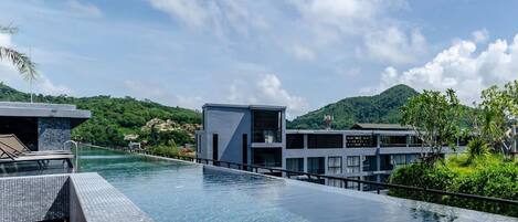 A modern hotel with a pool overlooking a mountainous landscape.