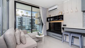 A modern living room with a sofa, a small round table with a vase, a flat-screen TV, and a fireplace. - Citygate Kamala Residence P506  (Kamala)