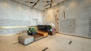Un área de recepción moderna con una pared de mármol, un mostrador de recepción y un espacio de espera.
