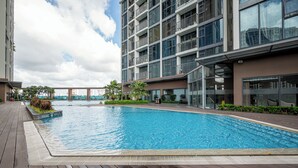 Un edificio moderno con piscina, terraza de madera y ventanas de vidrio.