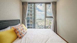 Un dormitorio con una cama grande, vistas a un paisaje urbano a través de una ventana y un diseño moderno.