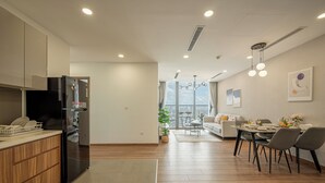 Una cocina moderna con refrigerador empotrado, armarios de madera y un comedor con mesa y sillas.