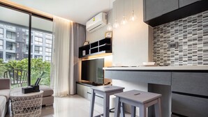 A modern kitchen with a large window, a built-in oven, and a dining area with stools. - Citygate Kamala Residence P204 (Kamala)