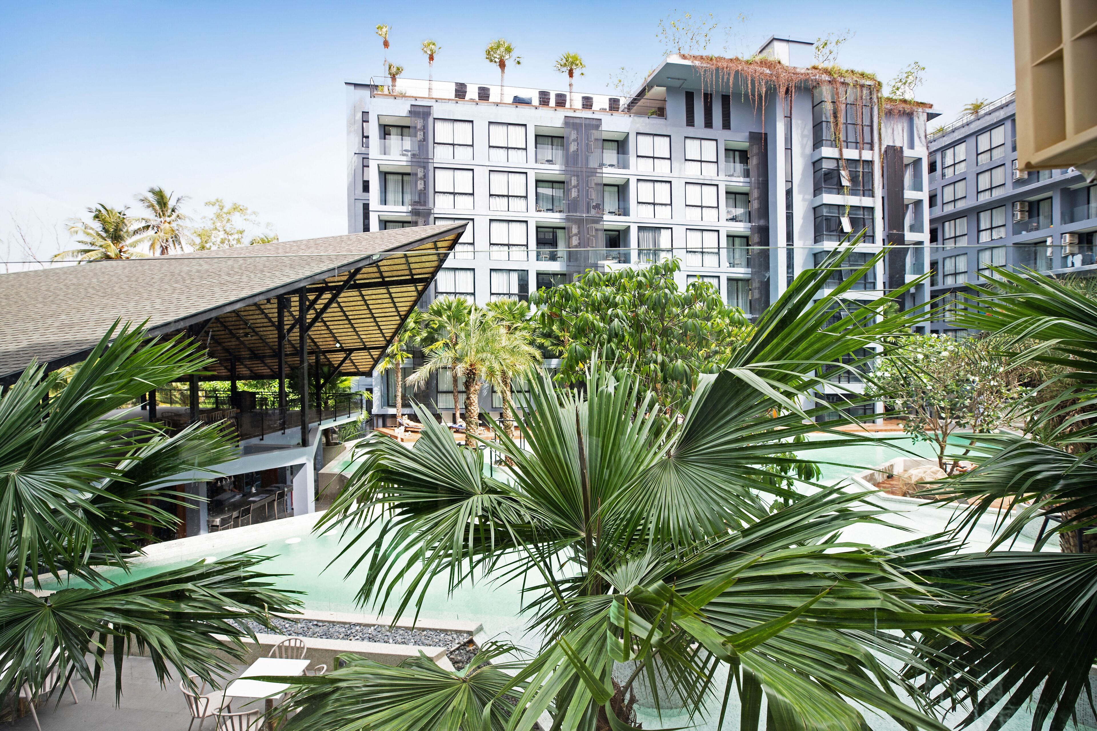 A hotel with a pool area surrounded by palm trees and a covered seating area.