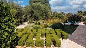 Un jardin avec des haies soigneusement taillées qui forment le mot « PALACE » et un chemin en pierre.