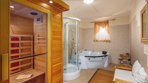 Une salle de bain moderne avec un sauna en bois, une douche à parois de verre, une grande baignoire et un banc en bois.