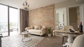 Een moderne woonkamer met een bakstenen muur, een bank, een salontafel en een eethoek met een tafel gedekt voor twee personen.