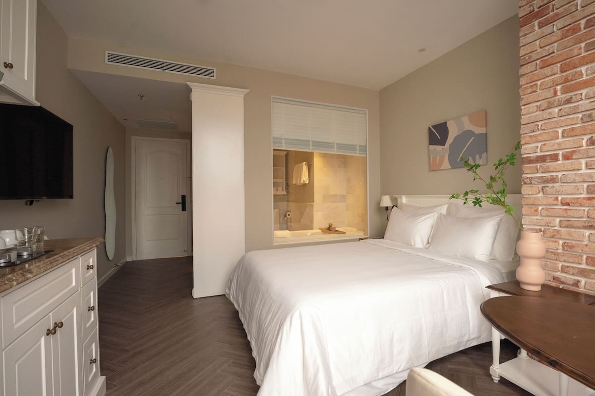 Ein Schlafzimmer mit einem großen Bett, einer eingebauten Fensterbank, einer Ziegelwand und einem Flachbildfernseher.